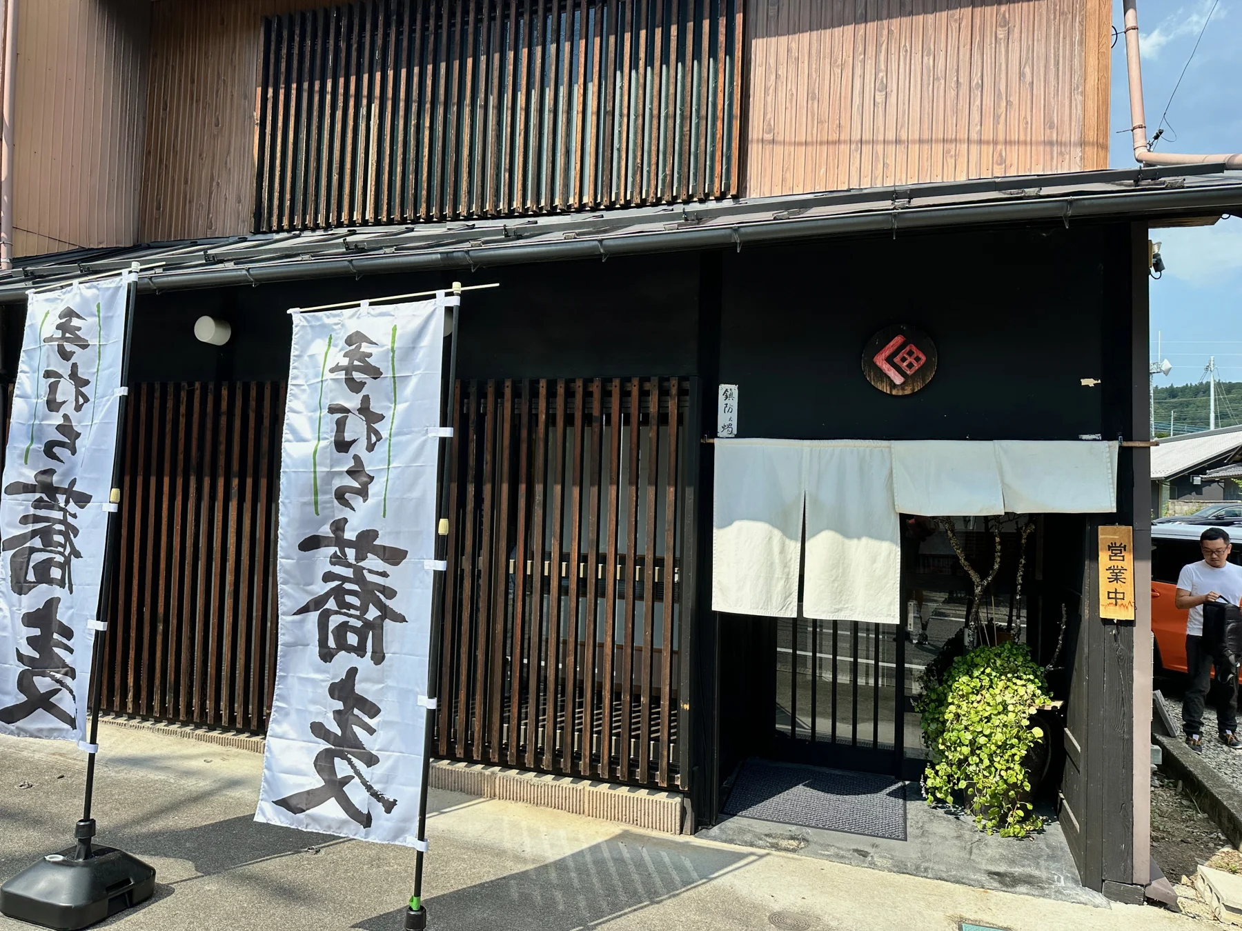 白いのれんとそばの旗が目印の、くぼ田の外観
