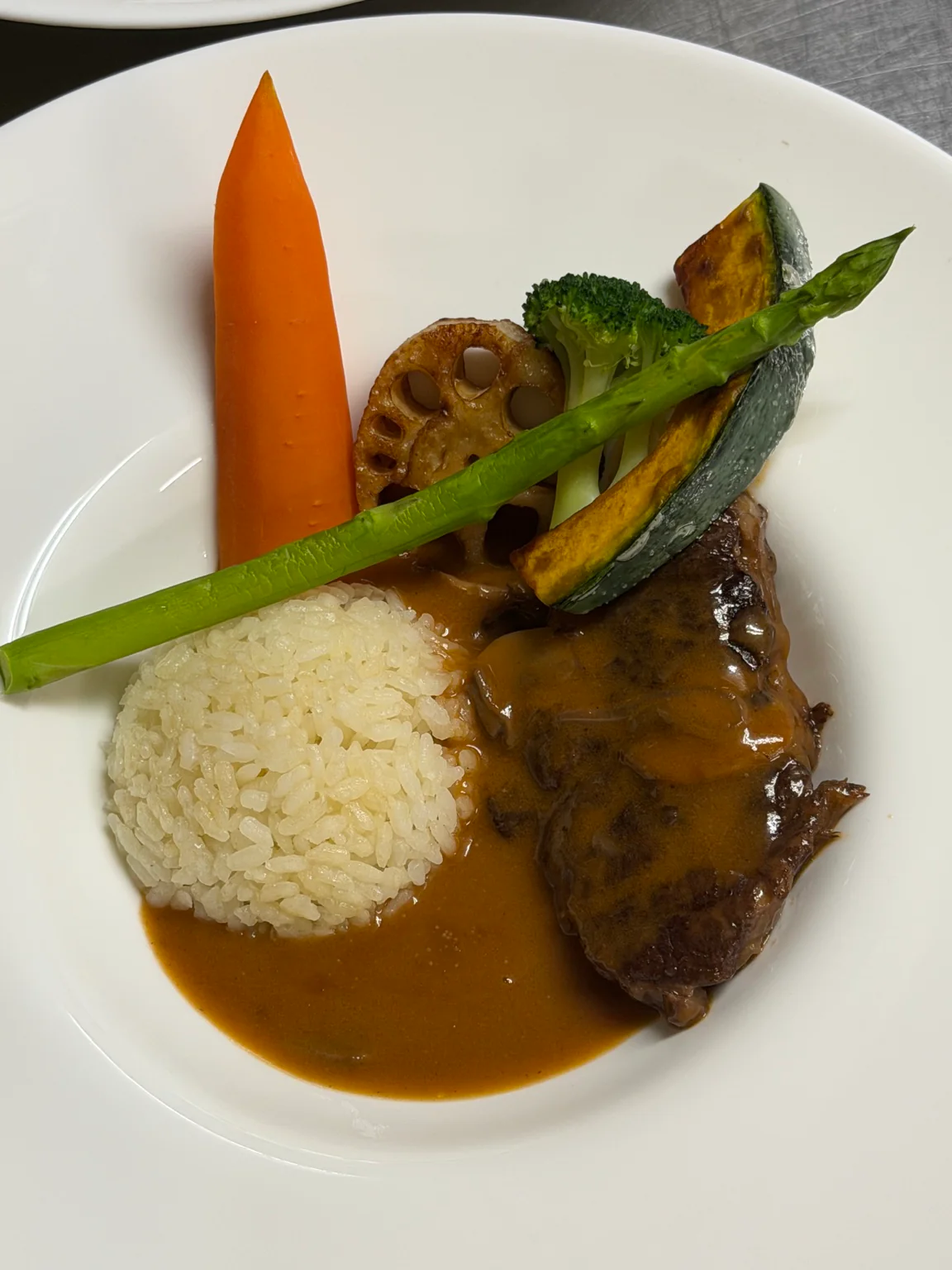 季節の野菜とライスを添えた肉料理