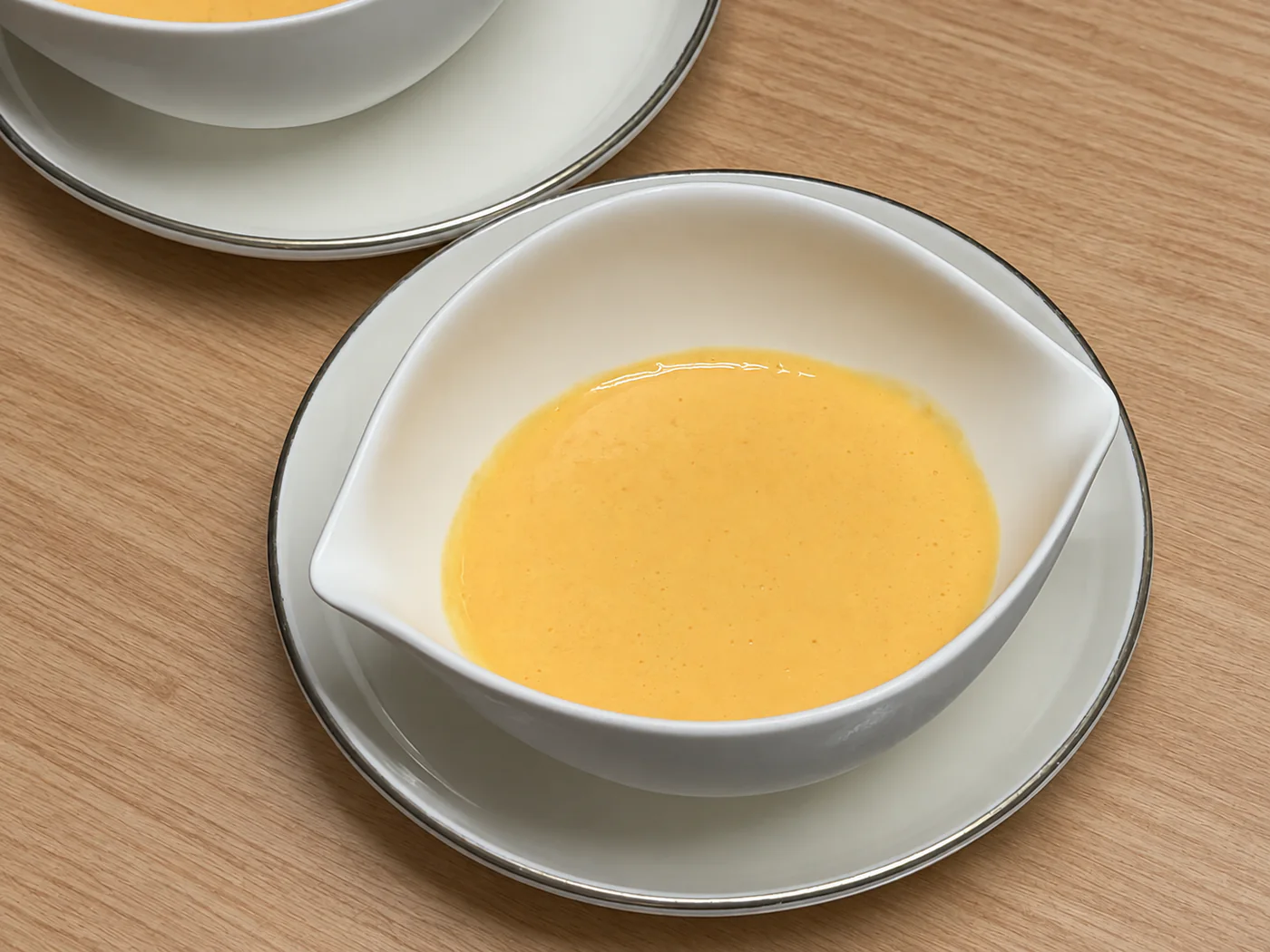 明るい木のテーブルに置かれたにんじんのスープ